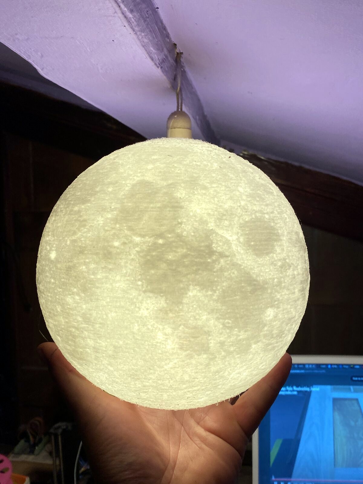 Lithophane moon lamp glowing in a dark room