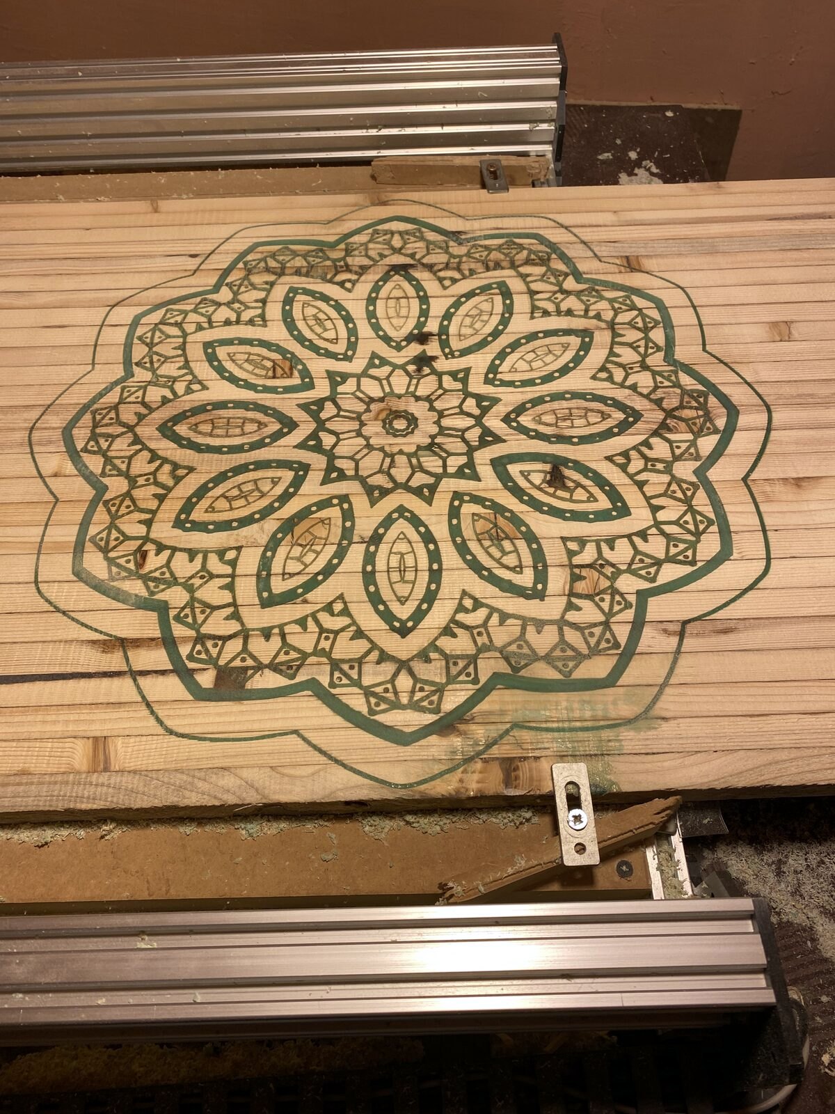 Wood panel clamped on the CNC machine bed during carving